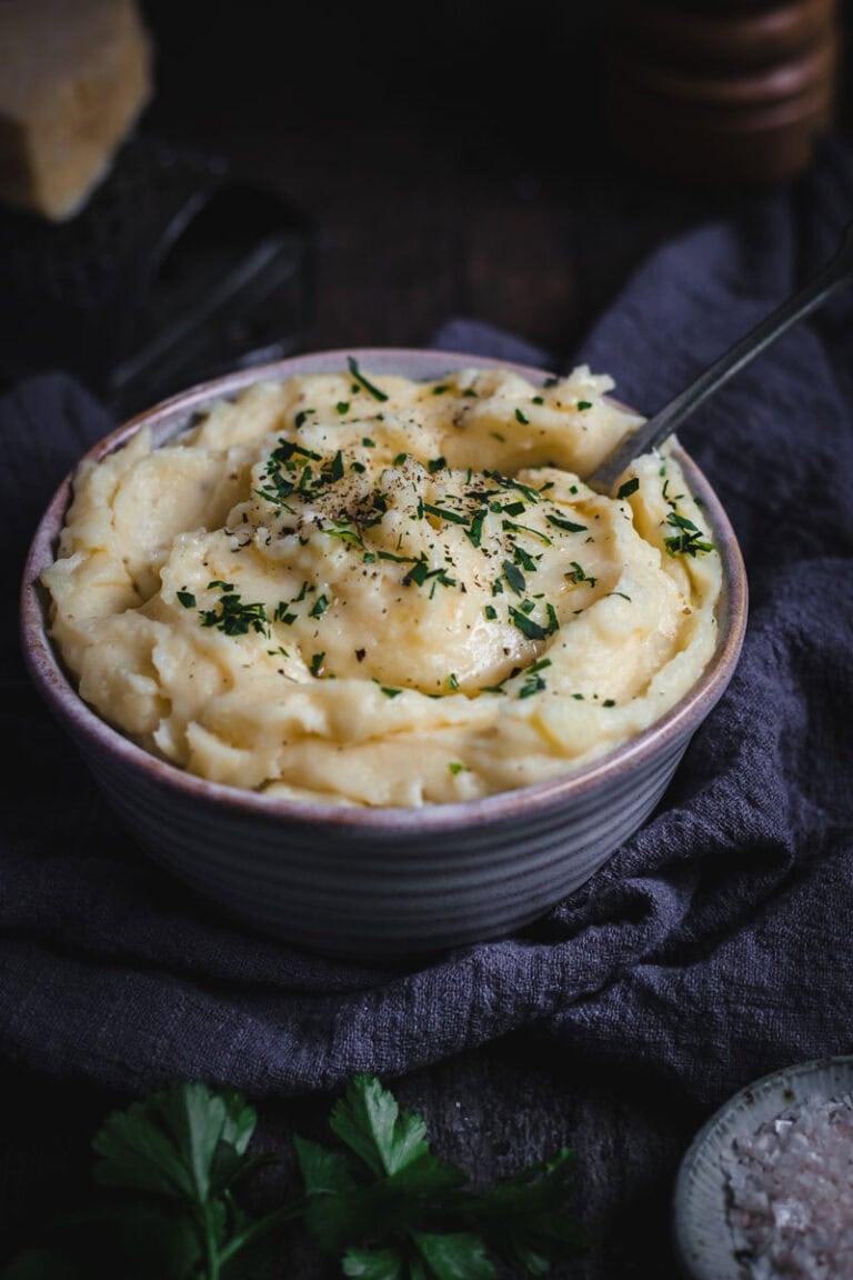 A bowl of Cheesy Mashed potatoes with parsley and salt.