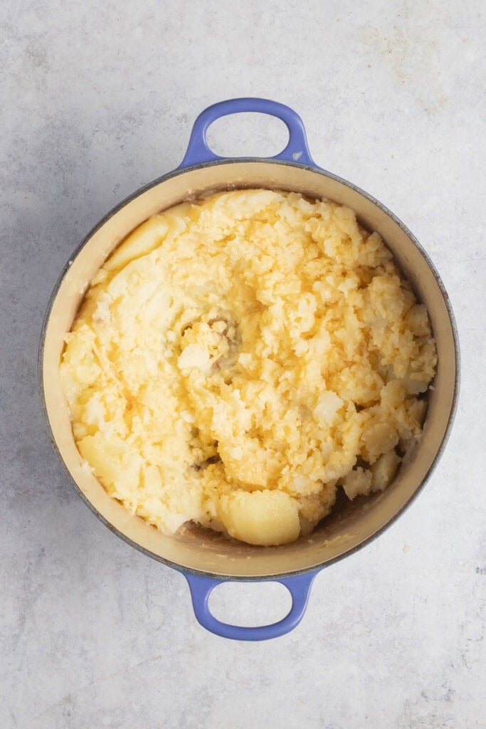Cheese being added to the pot of mash.