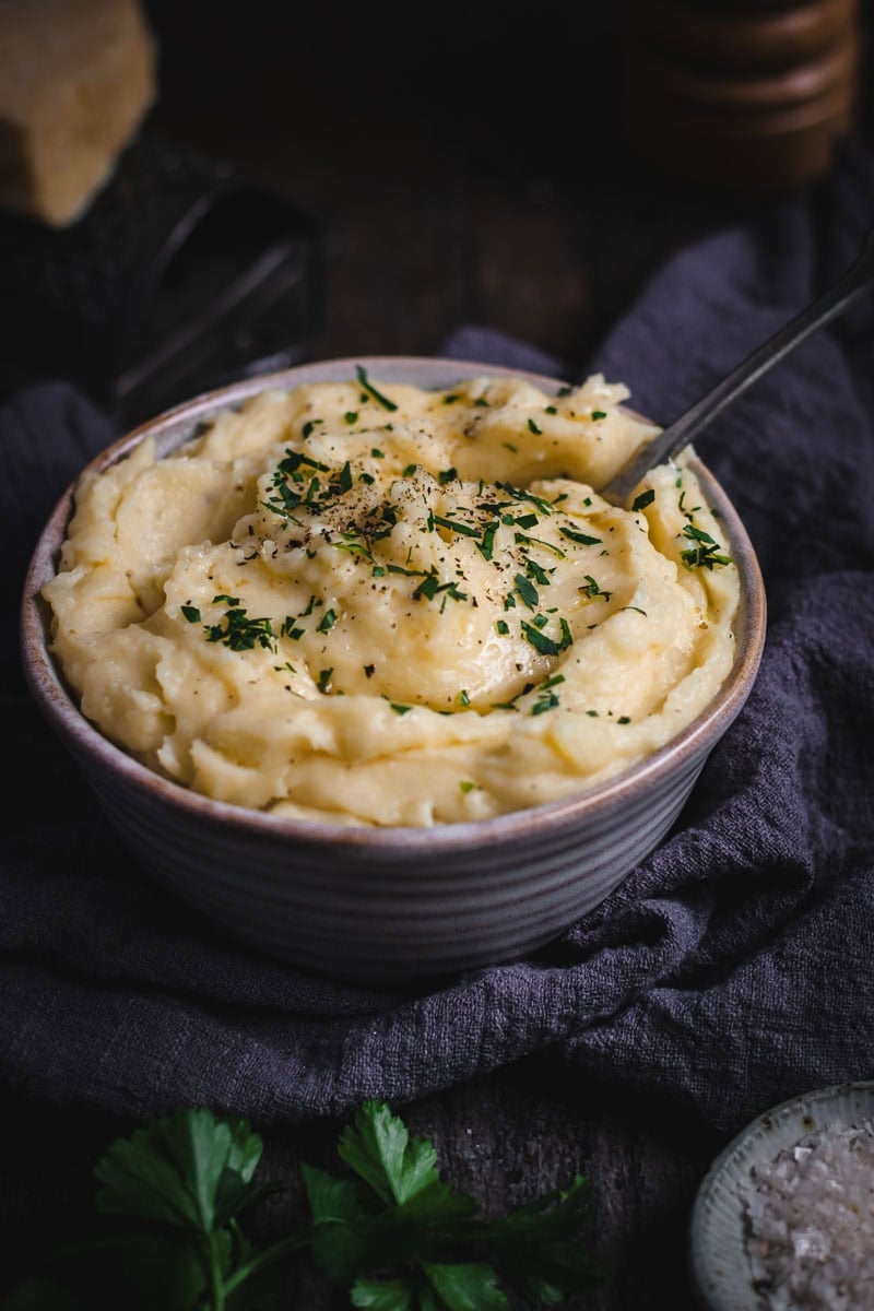 A bowl of Cheesy Mashed potatoes with parsley and salt.
