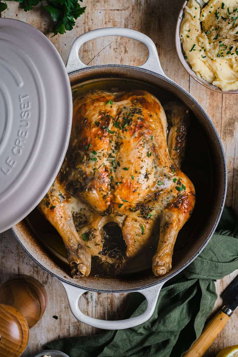 Le creuset pot with a cooked roast chicken in it.