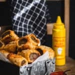 A tray of sausage rolls with ketchup and mustard.
