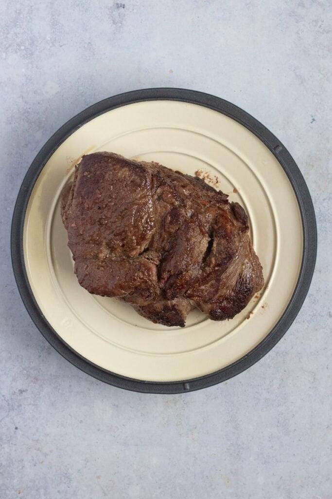 A piece of meat on a plate on a table.