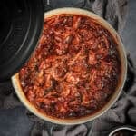 A black Dutch oven of BBQ pulled pork in it.