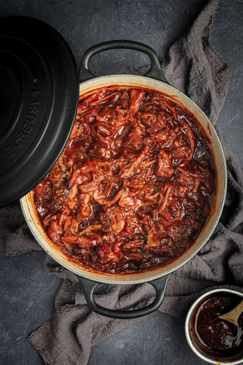 A black Le Creuset Casserole full of BBQ pulled pork.