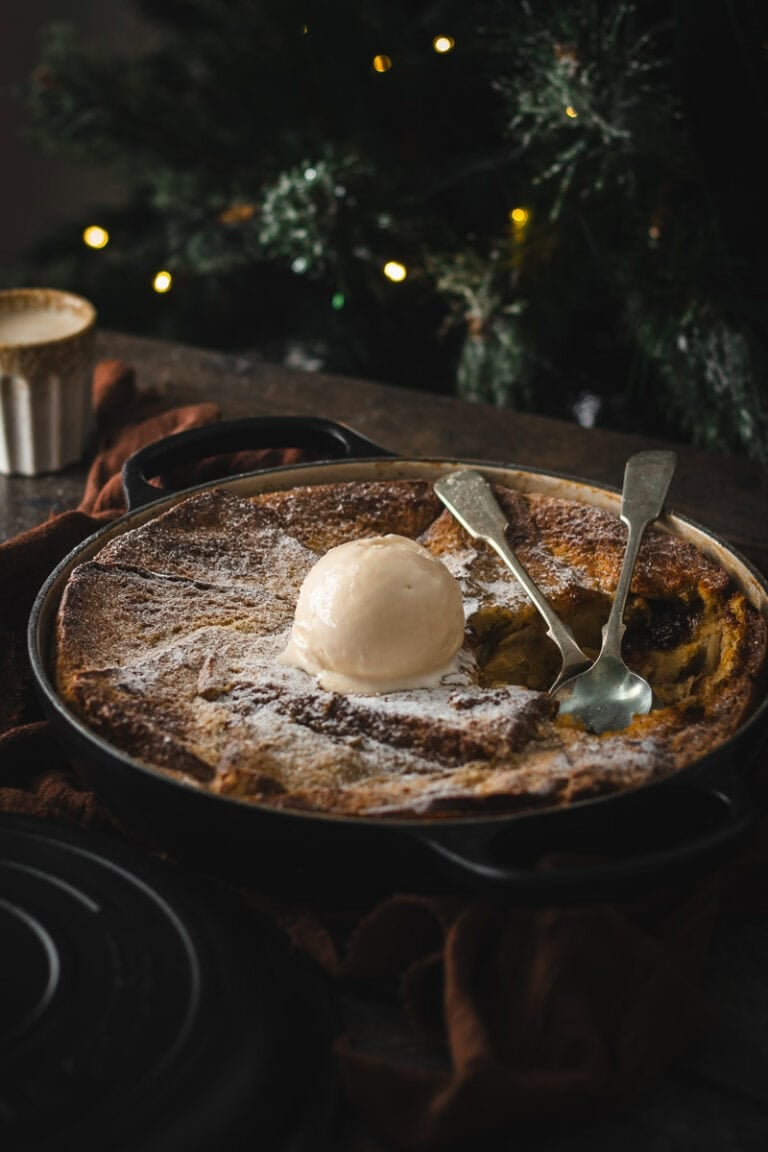 a shallow dutch oven by a Christmas tree with a bread and butter pudding baked in it.
