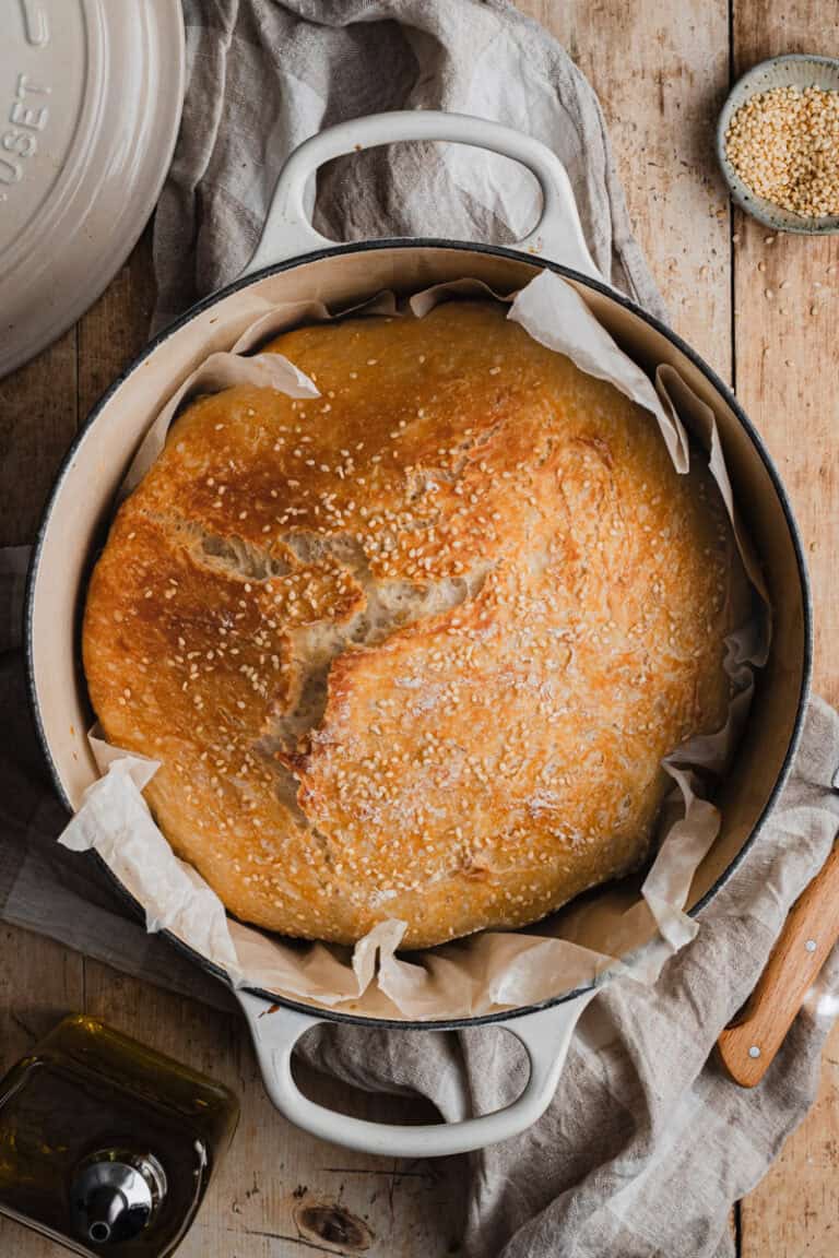 a cream dutch oven with a farmhouse loaf of bread in it.