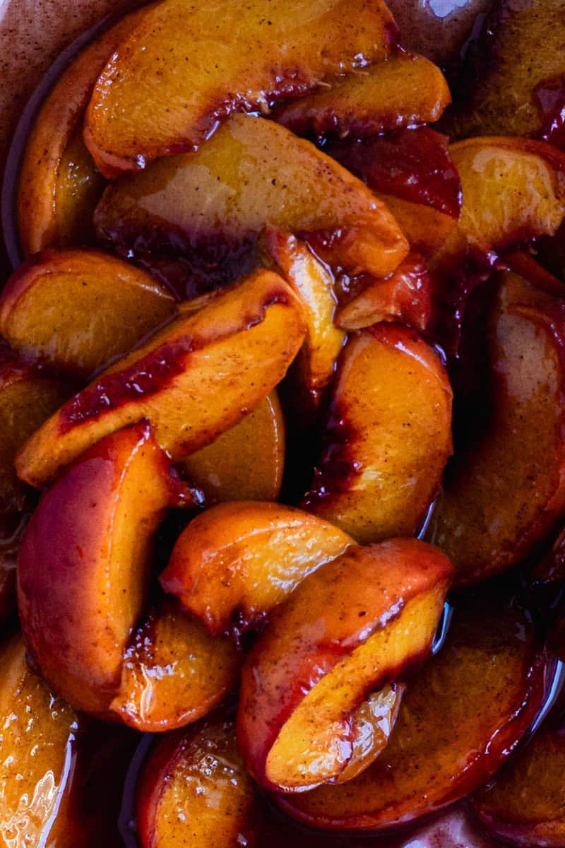 Close up of some roasted peaches, glistening in it's sugar glaze. 