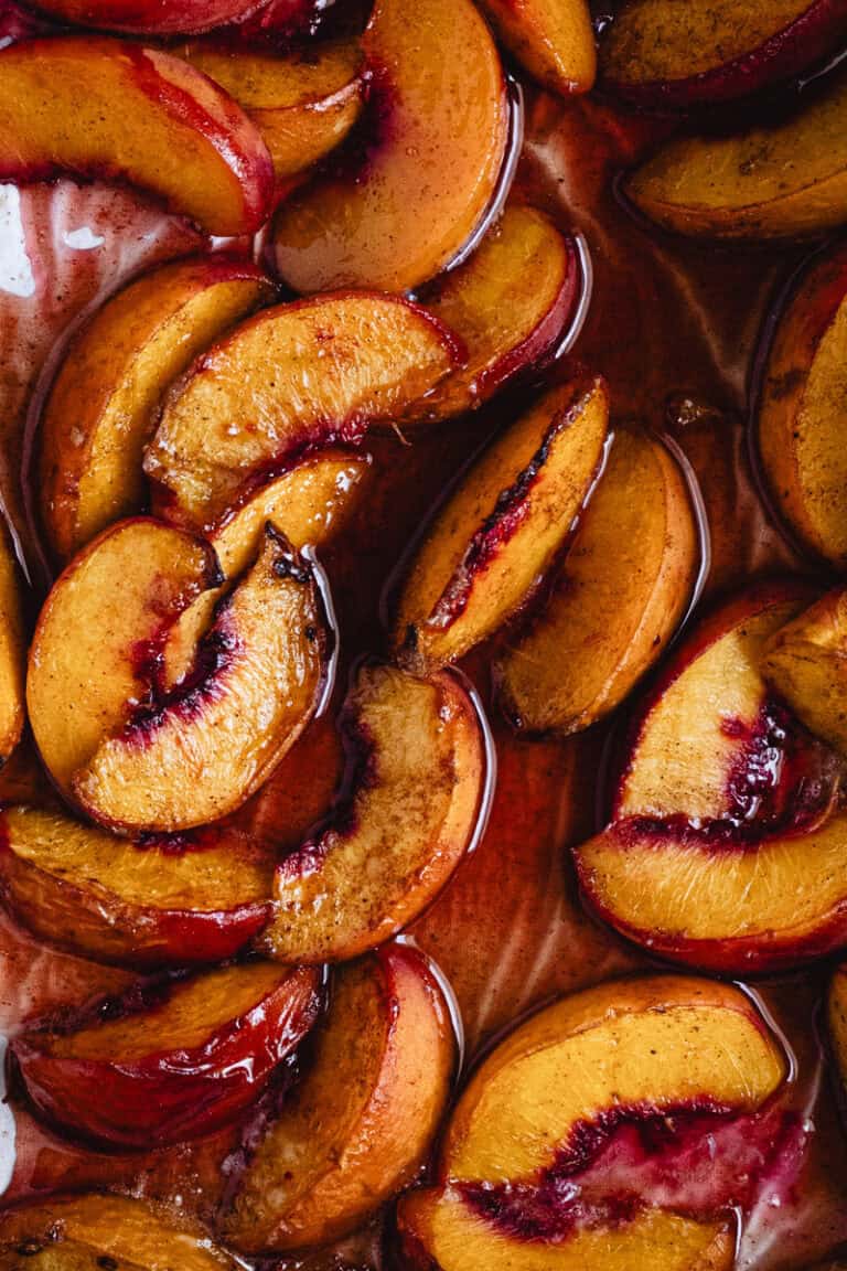 Close up of oven roast peaches on baking paper.