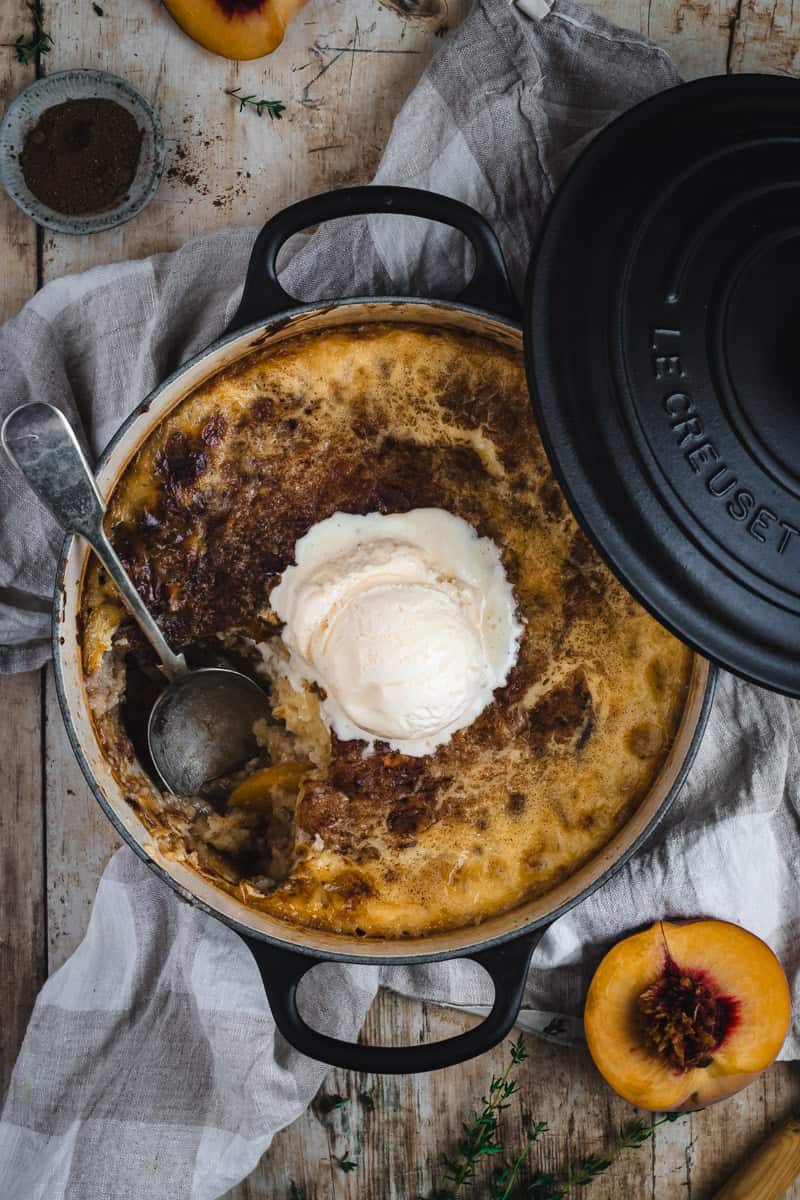 A dutch oven with a peaches and cream baked pudding in it.