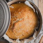 A loaf of no knead Dutch oven bread on a Dutch oven.