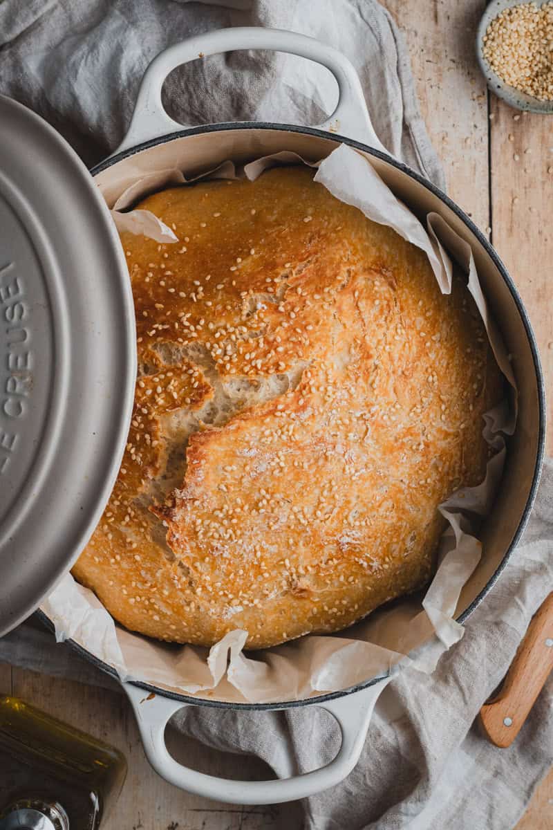 A loaf of no knead Dutch oven bread on a Dutch oven.