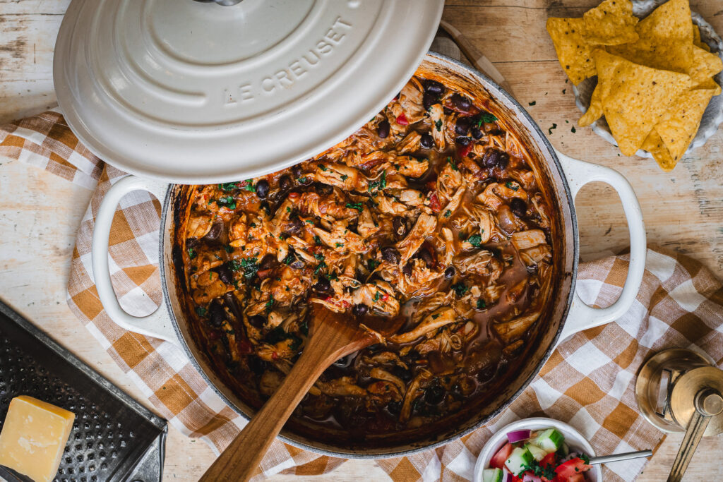 A cream enamel Dutch oven slow cooked with pulled chicken.