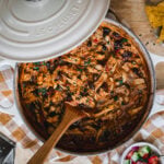 A cream enamel Dutch oven slow cooked with pulled chicken.