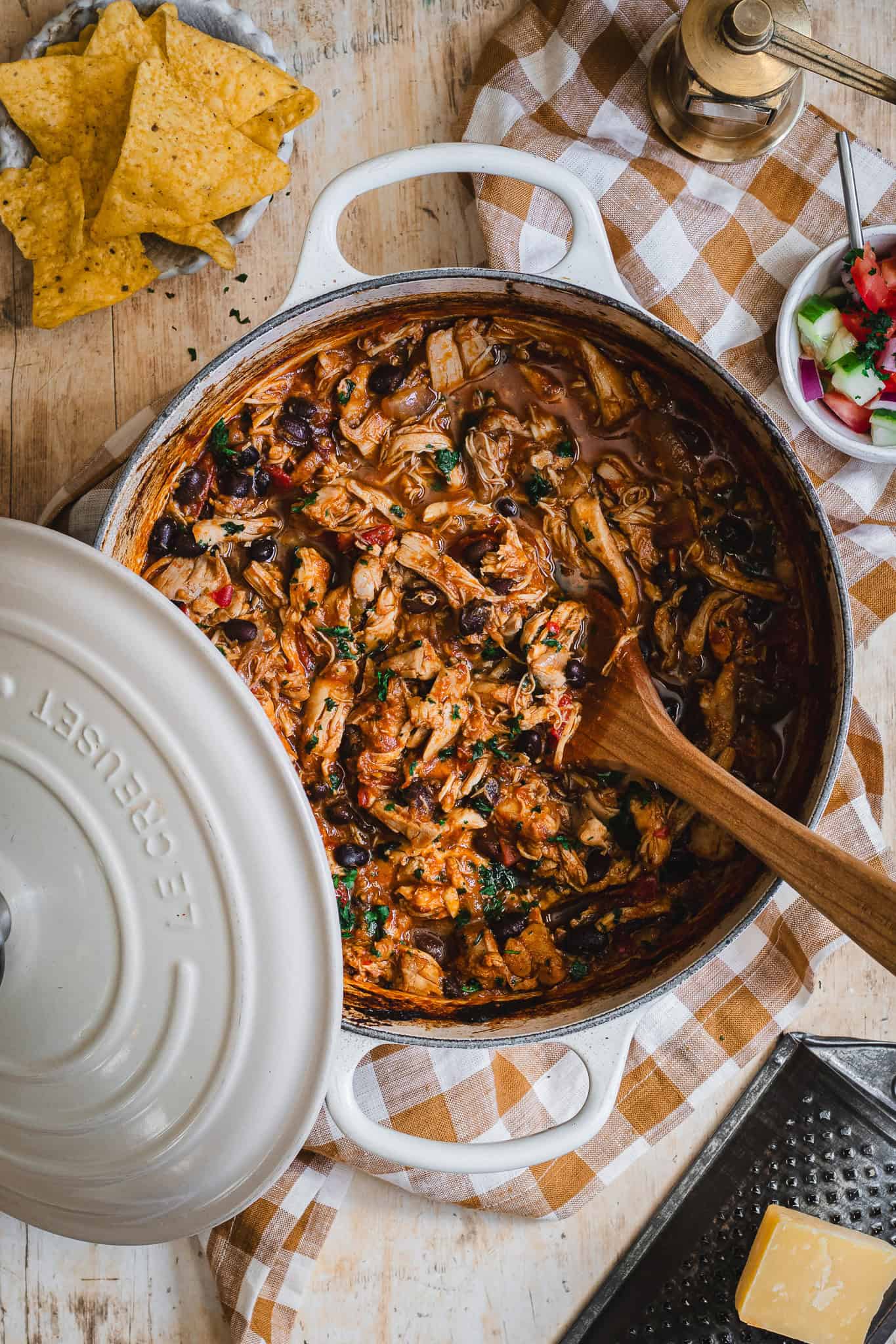 A cream enamel Dutch oven slow cooked with pulled chicken.