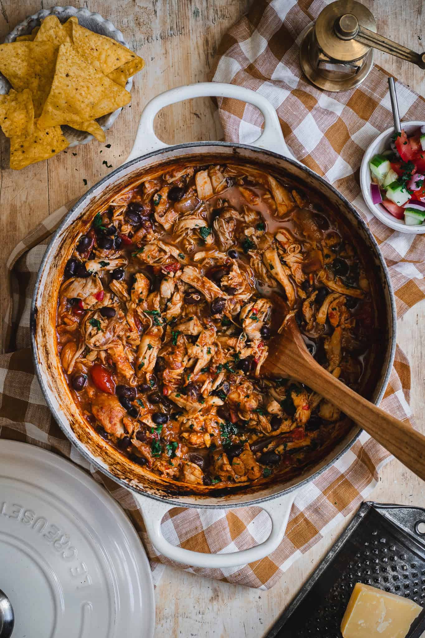 A Dutch of Pulled chicken with corn chips and a chopped salad to the side.