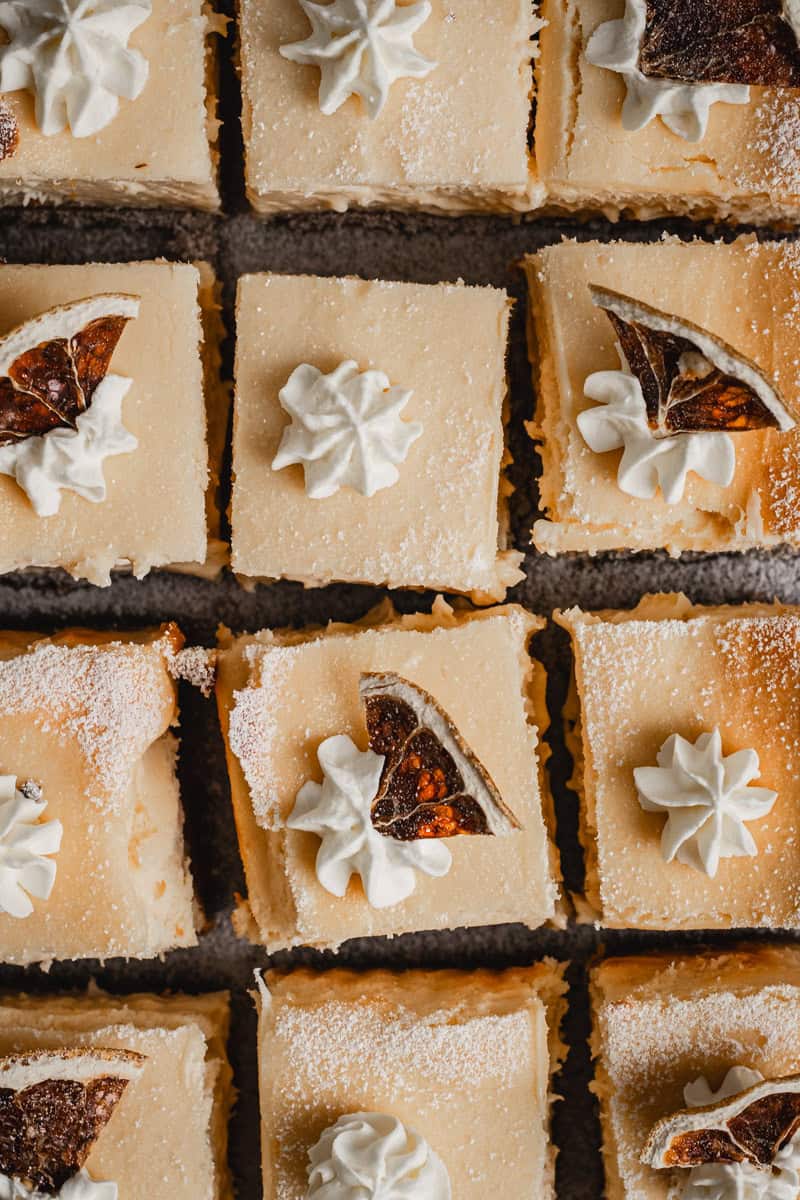 Bite sized pieces of lemon better baked cheesecake decorated with whipped cream and dehydrated lemon.